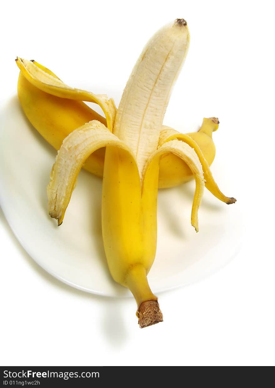 A peeled and an unpeeled fresh banana on white plate and isolated on white background. A peeled and an unpeeled fresh banana on white plate and isolated on white background