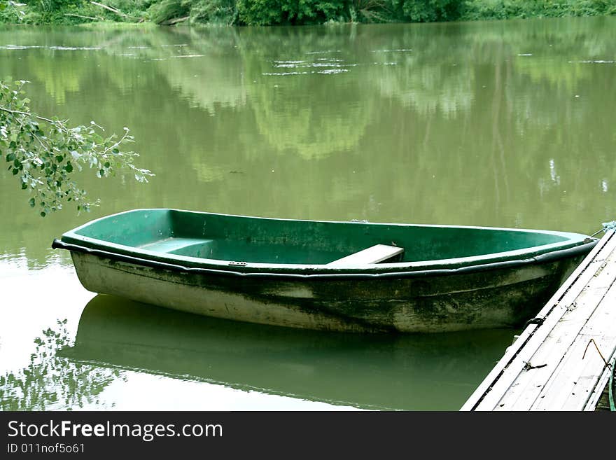 Abandoned green boat at the river, peacefull landscape.