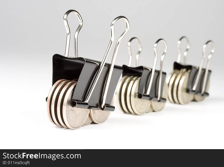 Coins clamped by a paper clip on a white background.