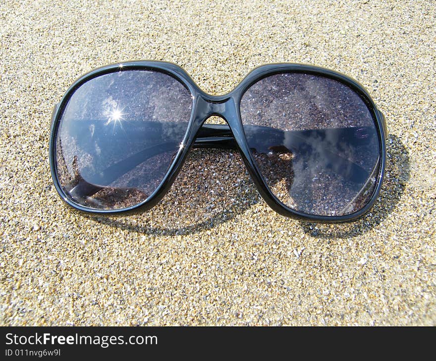 Sunglasses on a background of sand