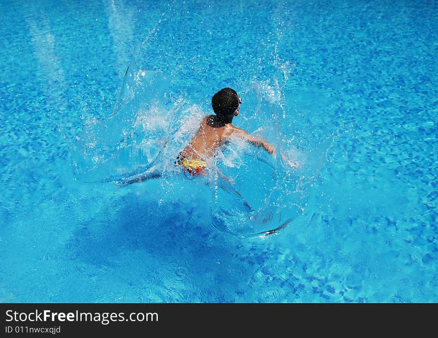 A boy jumps into the blue and clear water splashing big waves. A boy jumps into the blue and clear water splashing big waves.