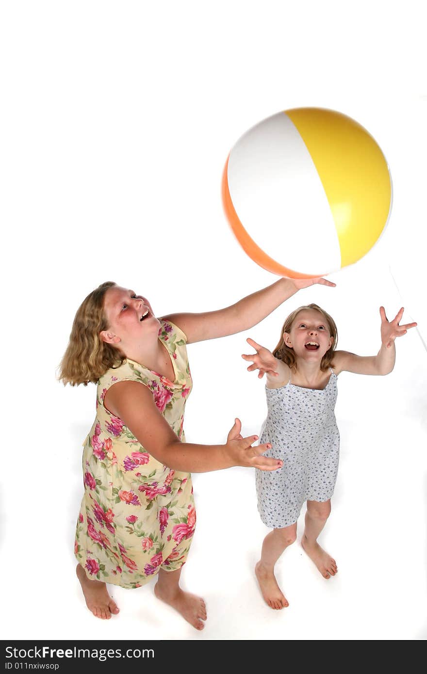 Two girls tossing ball in air