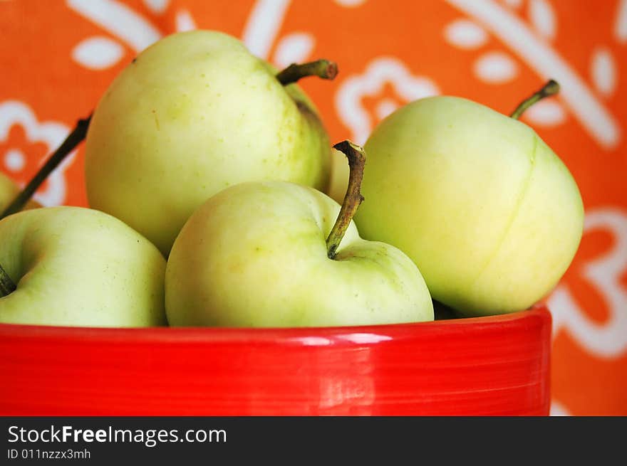 Green apples in a red bawl