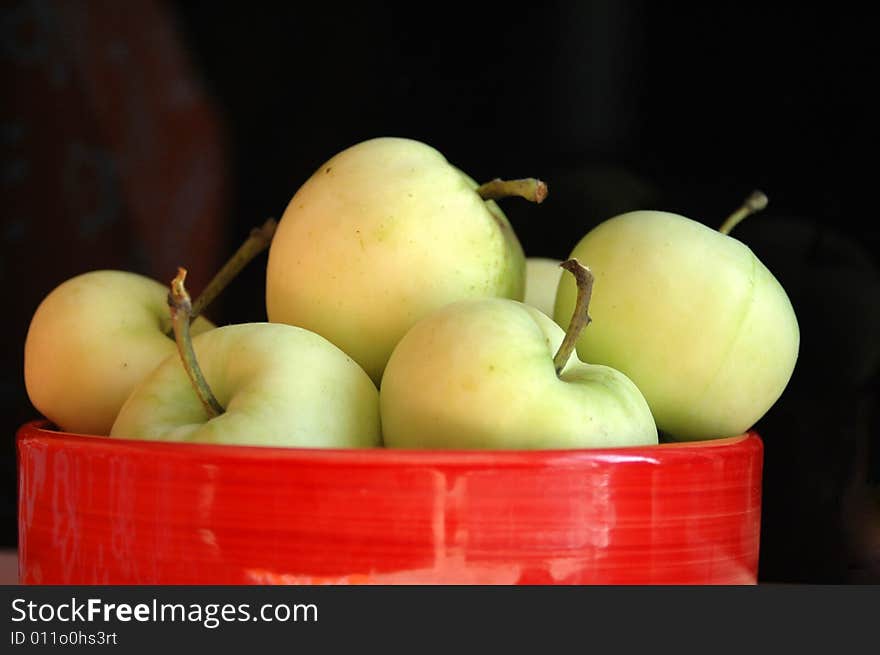 Green apples in a red bawl