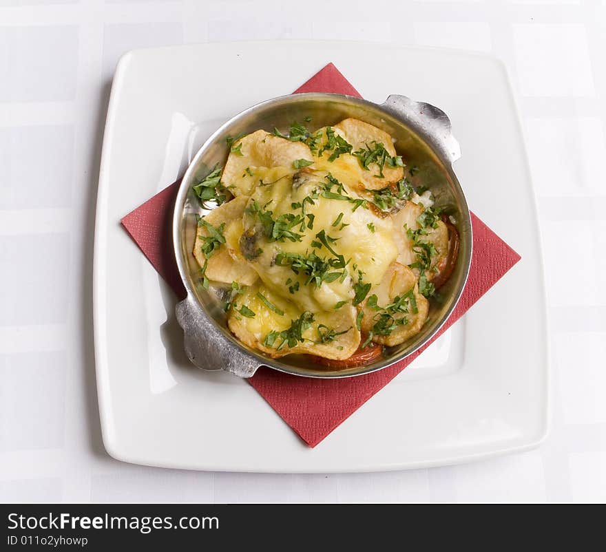 Sturgeon roasted under potatoes and cheese on the table