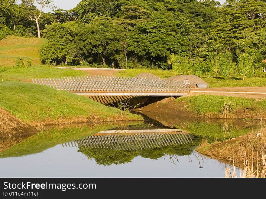 A lattice wood bridge over a lake with reflections in the water. A lattice wood bridge over a lake with reflections in the water