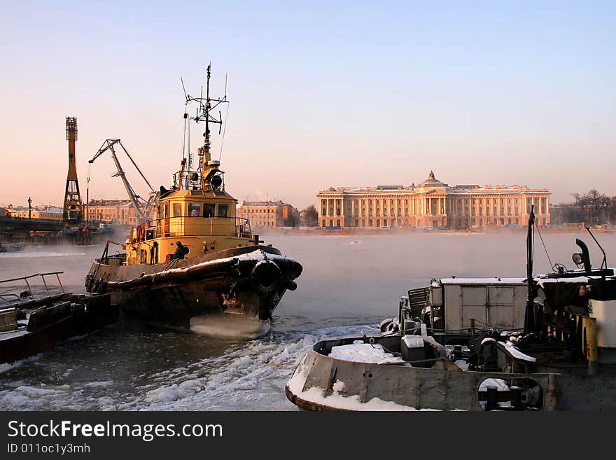 A small yellow river ice breaker near an embankment. A small yellow river ice breaker near an embankment