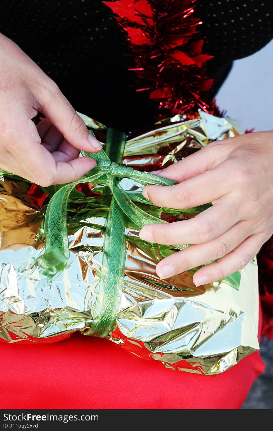 Close-up of a woman unwrapping a Christmas gift. Close-up of a woman unwrapping a Christmas gift.