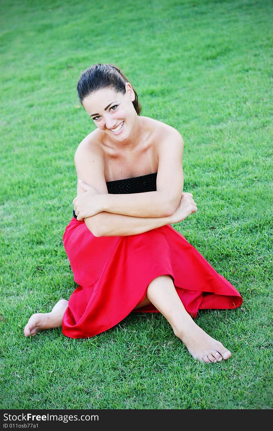 Beautiful young woman sitting outside on the grass. Beautiful young woman sitting outside on the grass.