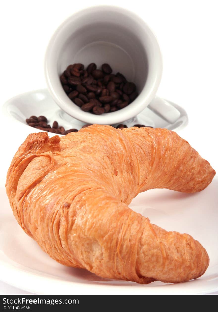 Croissant and cup with coffee beans