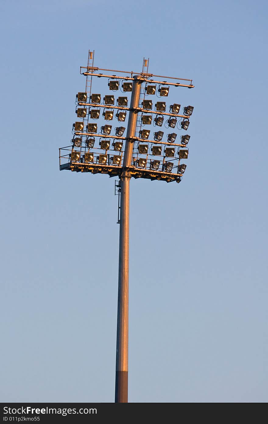 Stadium lights before sunset against sky