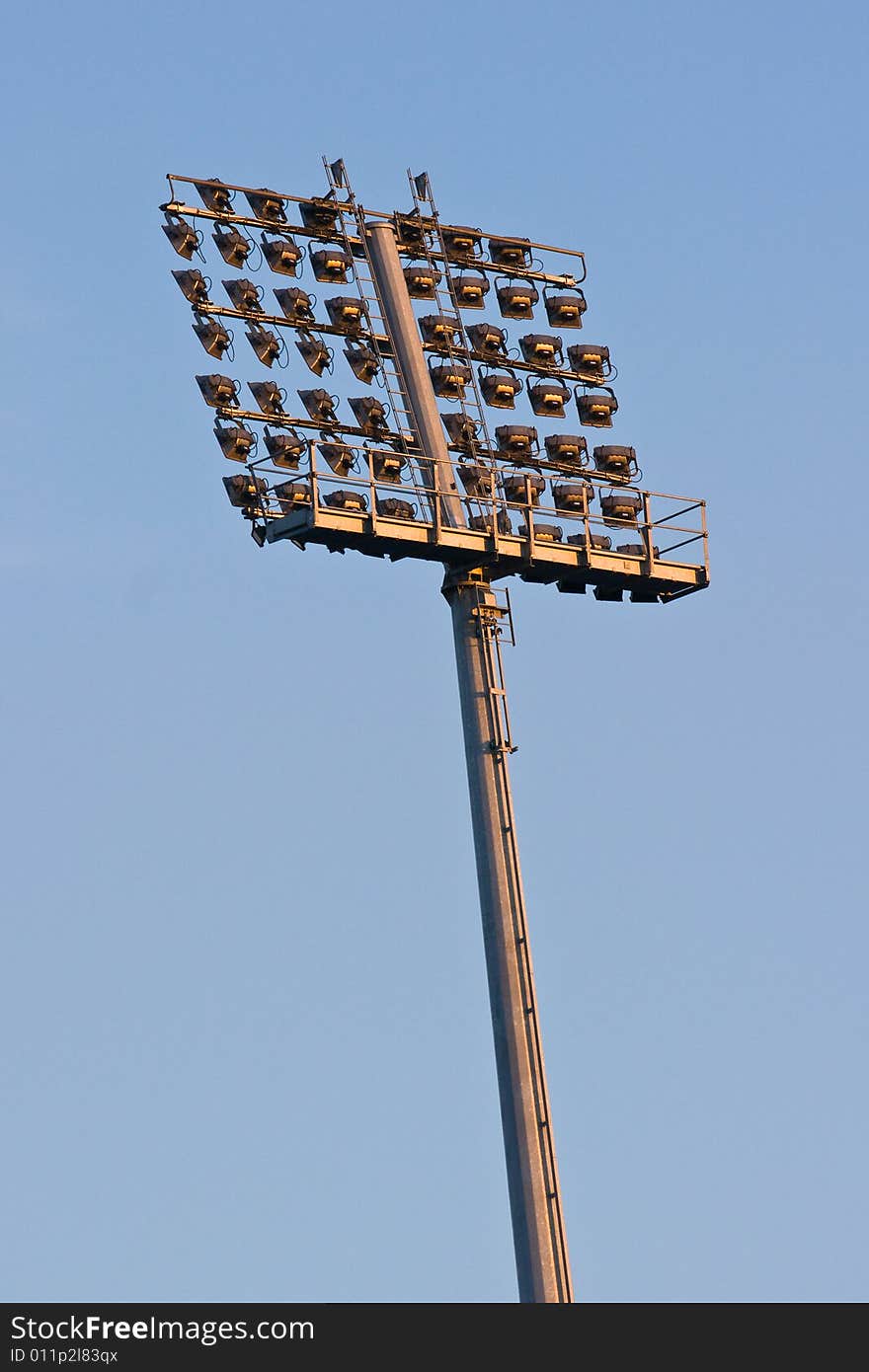 Stadium lights before sunset against sky