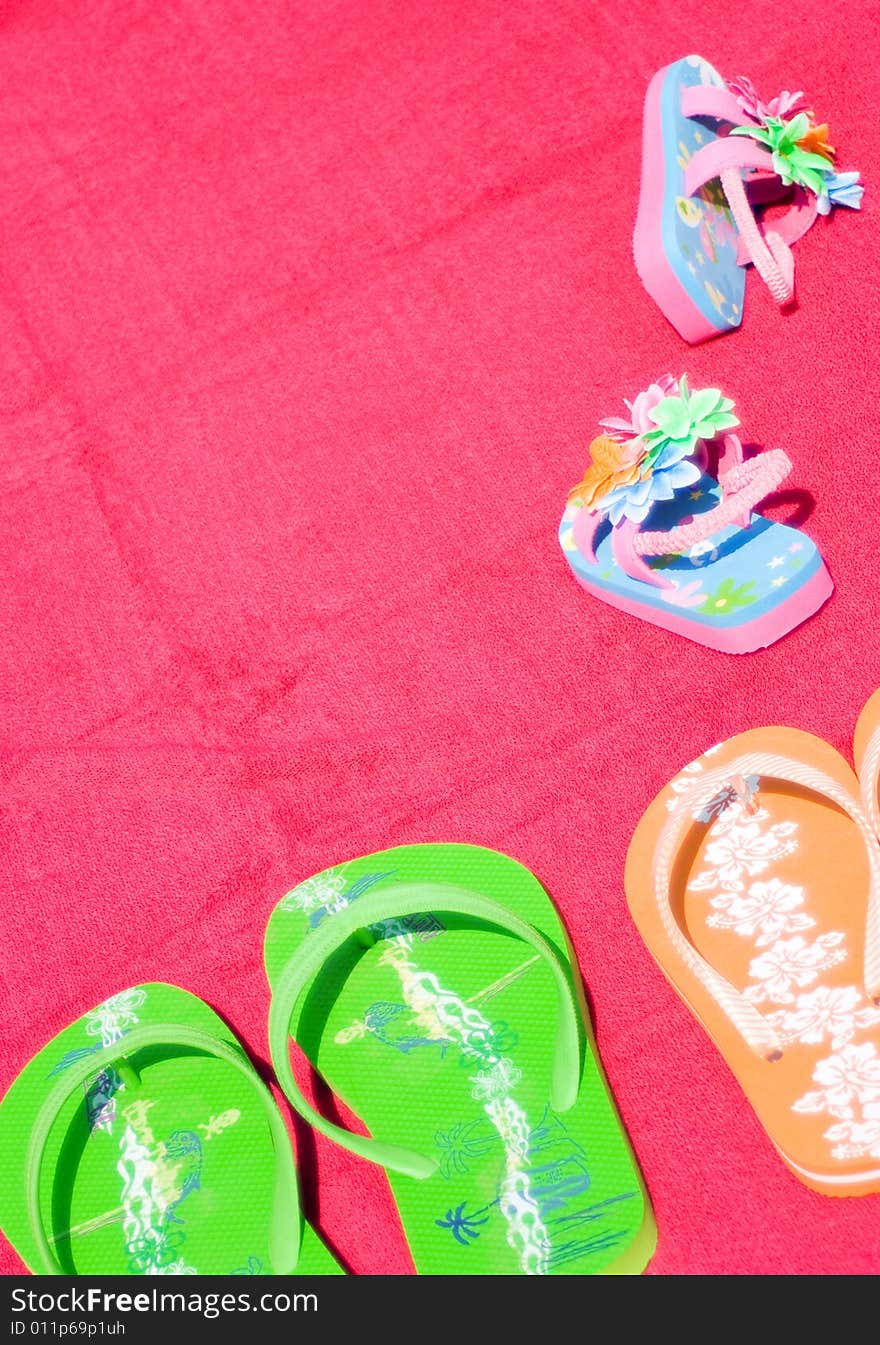 Three pairs of flipflops on red beachtowel. Symbol for dad, mum and the little daughter. Family on vacation, fun, sea and summer concept. Space for copy.