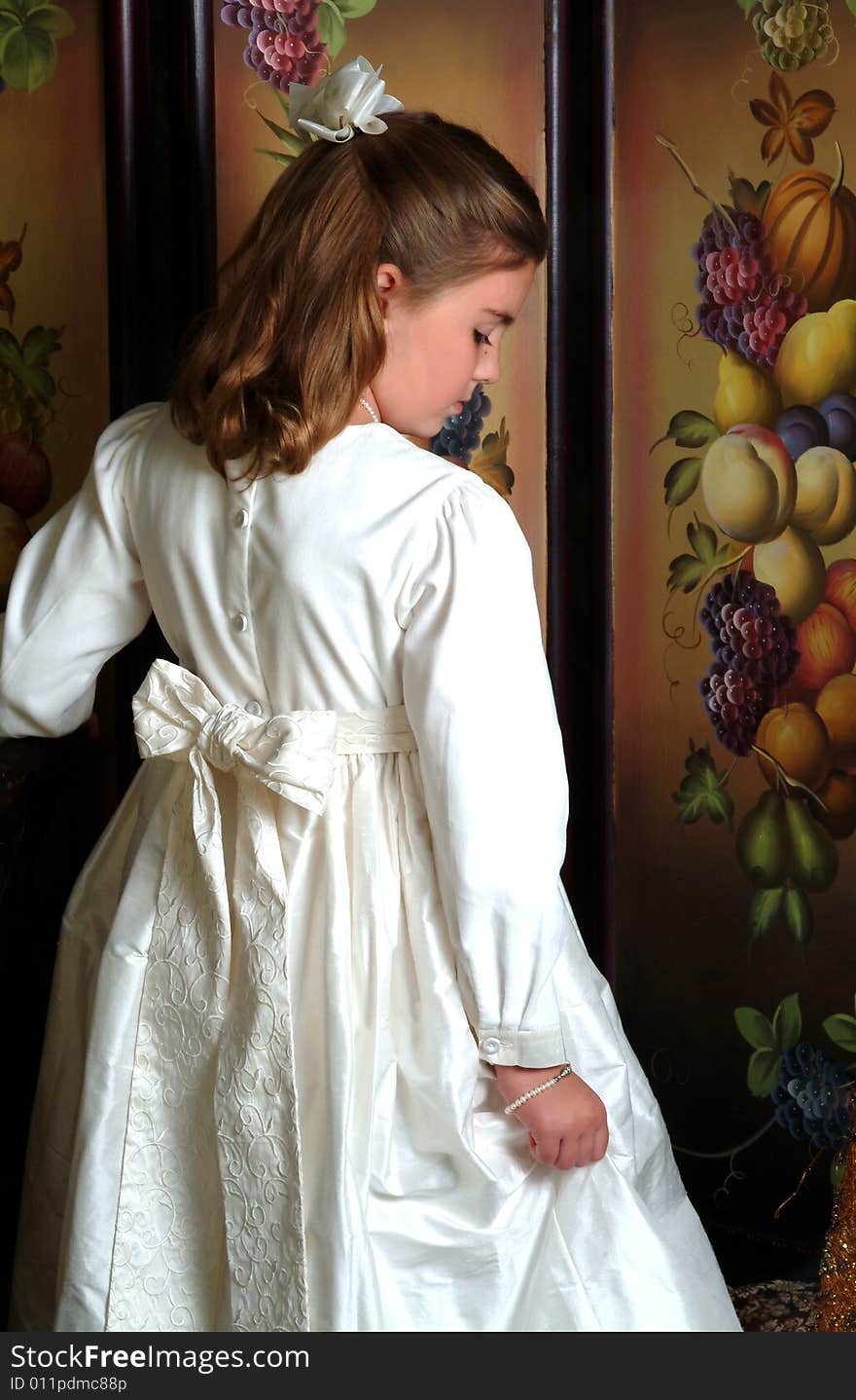 Back of winter white dress of school aged girl with solemn expression