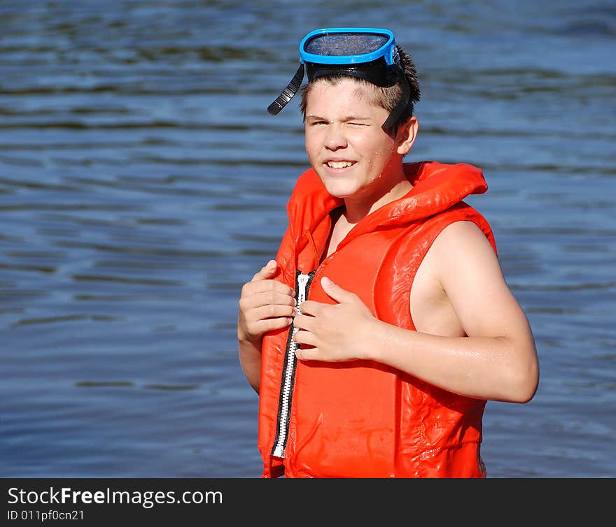 The boy with a life-jacket and a diving mask is ready for a good swim in the lake. The boy with a life-jacket and a diving mask is ready for a good swim in the lake.