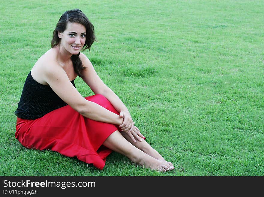 Portrait of a beautiful woman sitting on the grass.