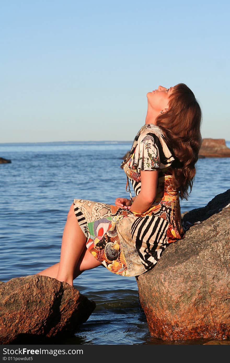 Young lady sitting on a stone and looking up to the skies. Young lady sitting on a stone and looking up to the skies