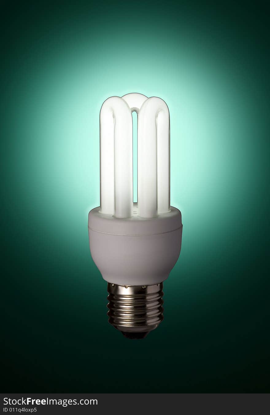 Glowing energy saving florescent light bulb with a green lightbulb. Glowing energy saving florescent light bulb with a green lightbulb