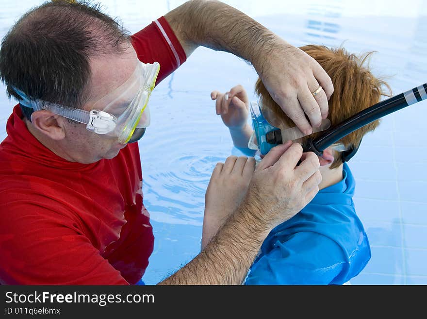 A father adjusting his son's snorkel and mask before swimming