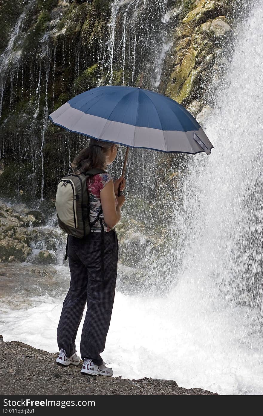 Tourist woman looking at a mountain waterfall. Tourist woman looking at a mountain waterfall