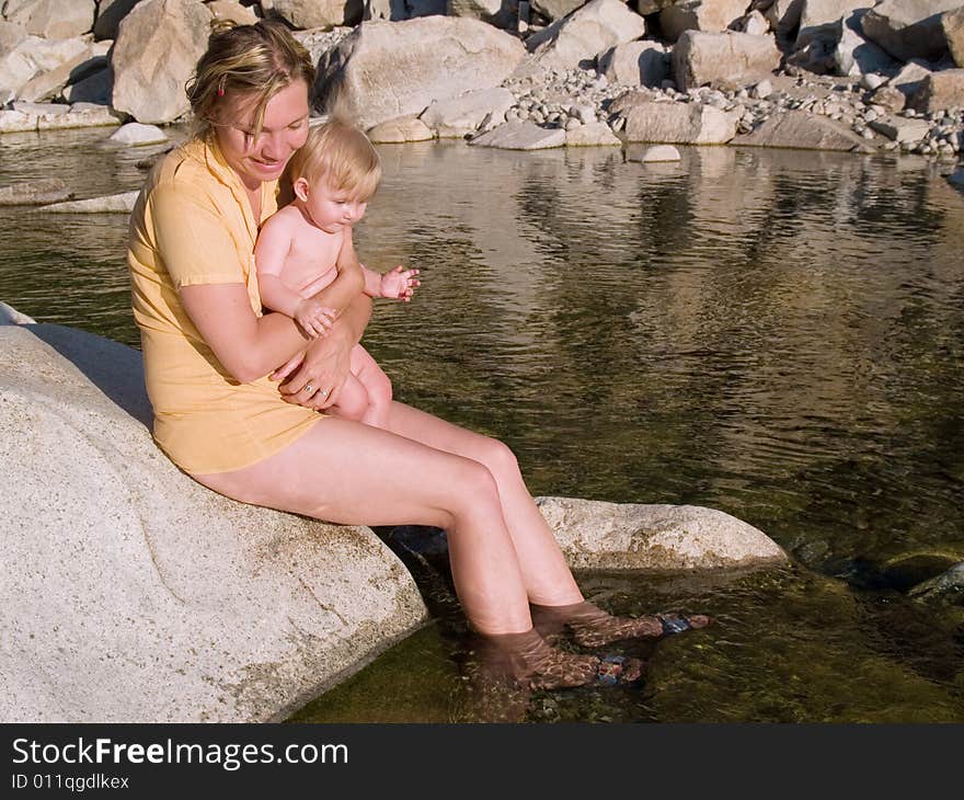 Mother with child sit near water