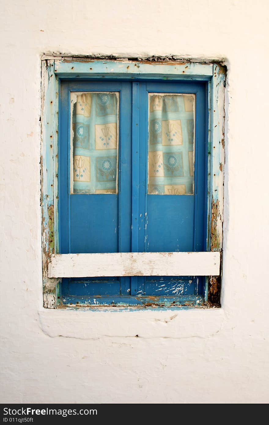 A blue shut window on a white wall