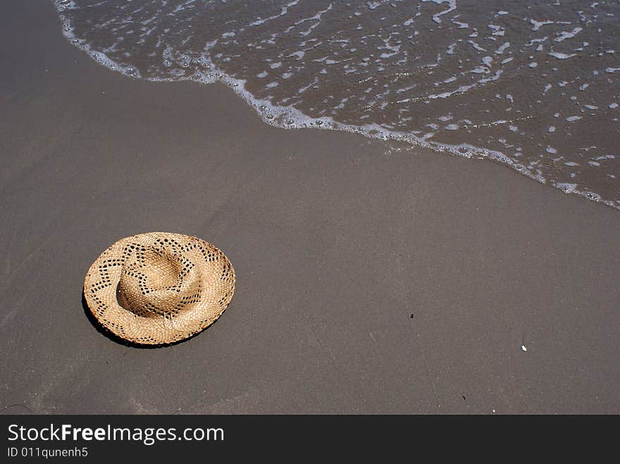 In this photo is situated a hat at the send, and surf.