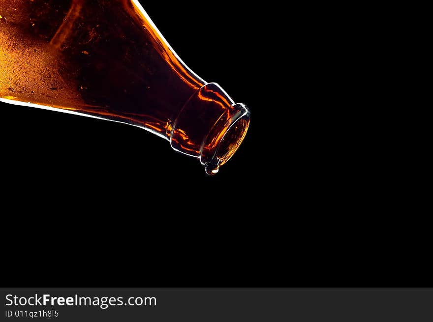 Close-up drop falling from bottle isolated on black