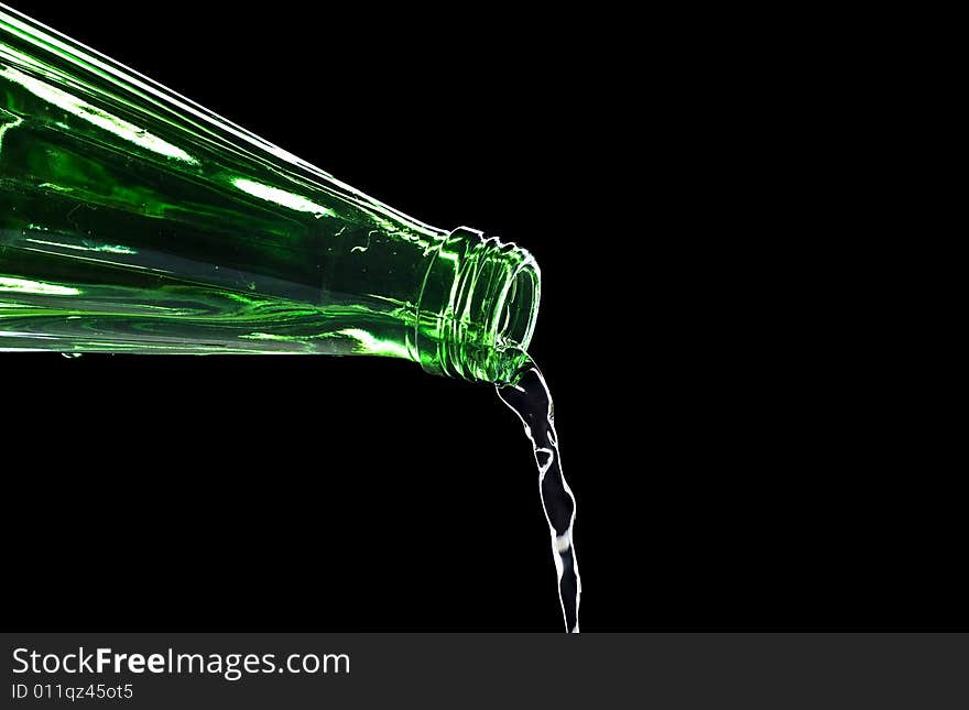 Flowing water from bottle isolated on black