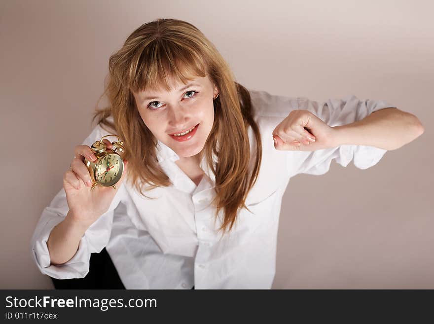 A young woman with alarm clock in her arm