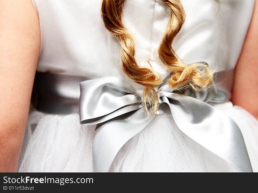 Twirled locks of golden hair against a flower-girl dress