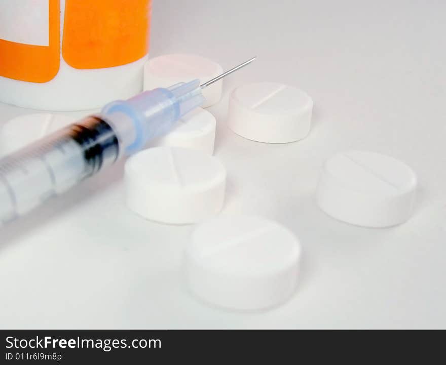 Tablets a syringe and a drug container on a white surface. Tablets a syringe and a drug container on a white surface