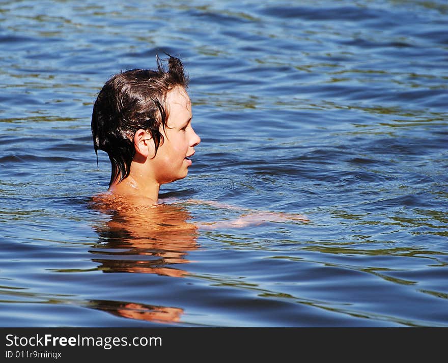 The profile of the boy swimming deep in a lake. The profile of the boy swimming deep in a lake.