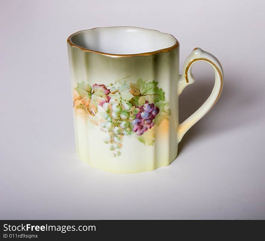 A china cup with grapes and leaves on it