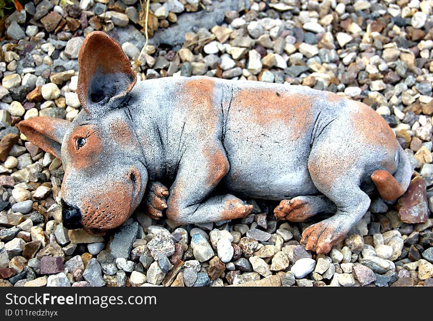 Toy ceramic dog lying on stones. Toy ceramic dog lying on stones