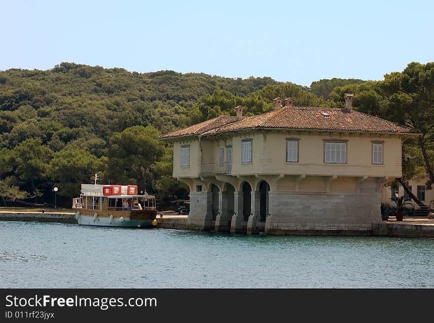 Photo of a large house built at the Mediterranean coast and promenade ship near it. Photo of a large house built at the Mediterranean coast and promenade ship near it