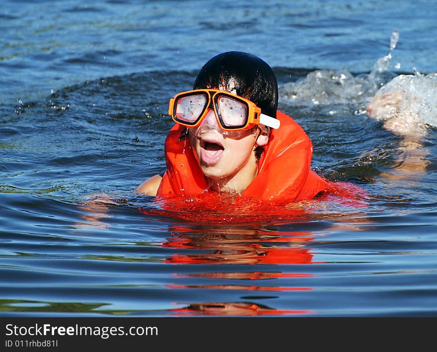 The boy is trying to swim with a diving mask that became misted. The boy is trying to swim with a diving mask that became misted.