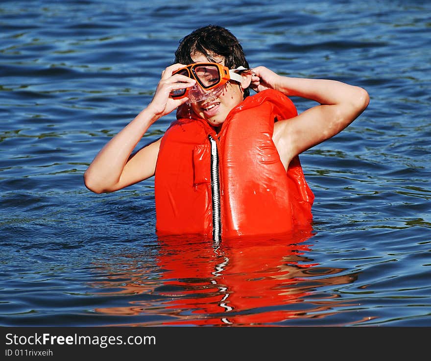 The boy with a life-jacket and a diving mask having fun in a small lake late afternoon. The boy with a life-jacket and a diving mask having fun in a small lake late afternoon.