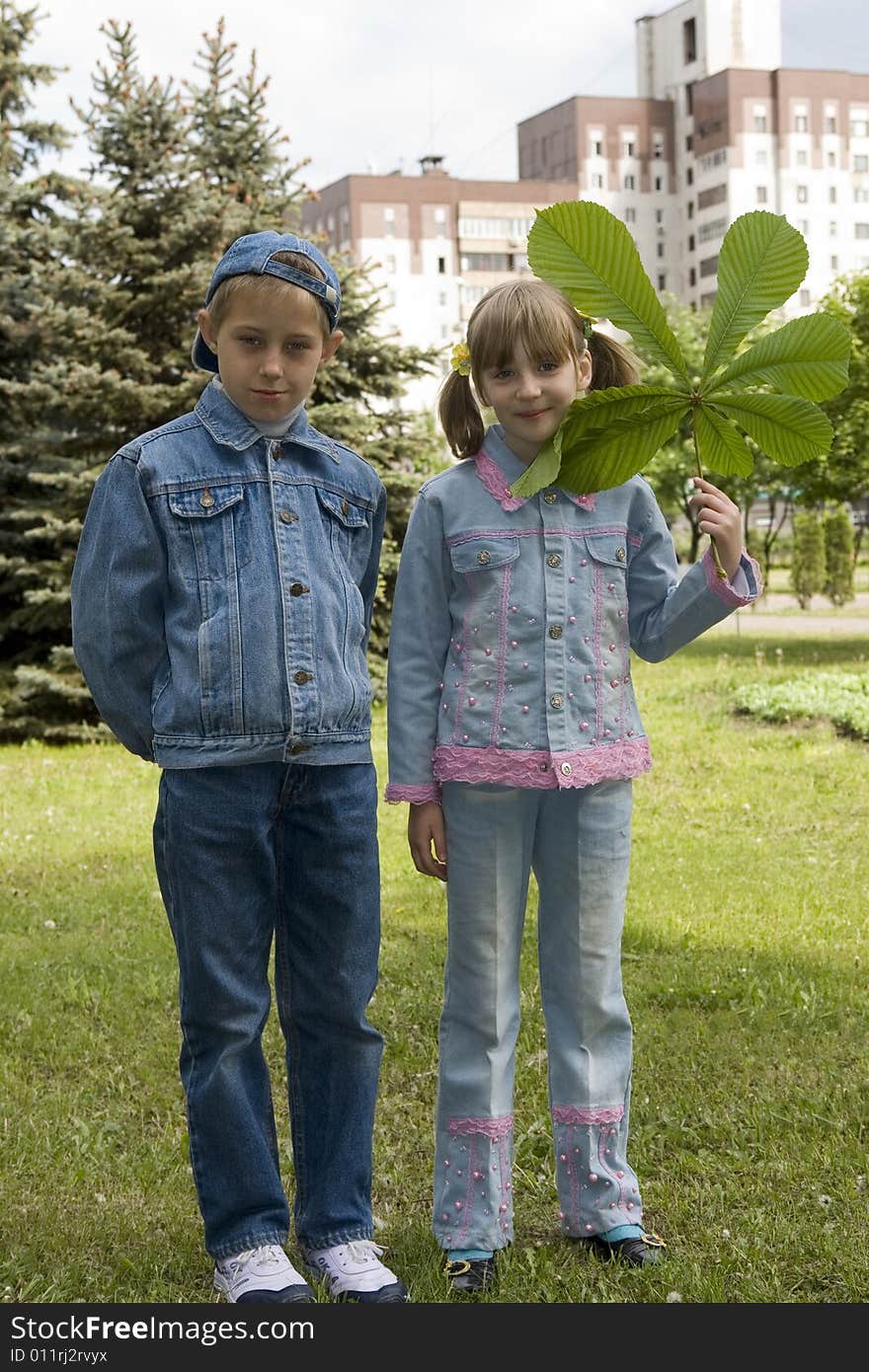 The boy and the girl play with leaves