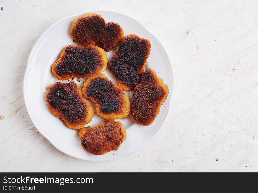 Slightly burnt chicken cutlets on the plate. Slightly burnt chicken cutlets on the plate.