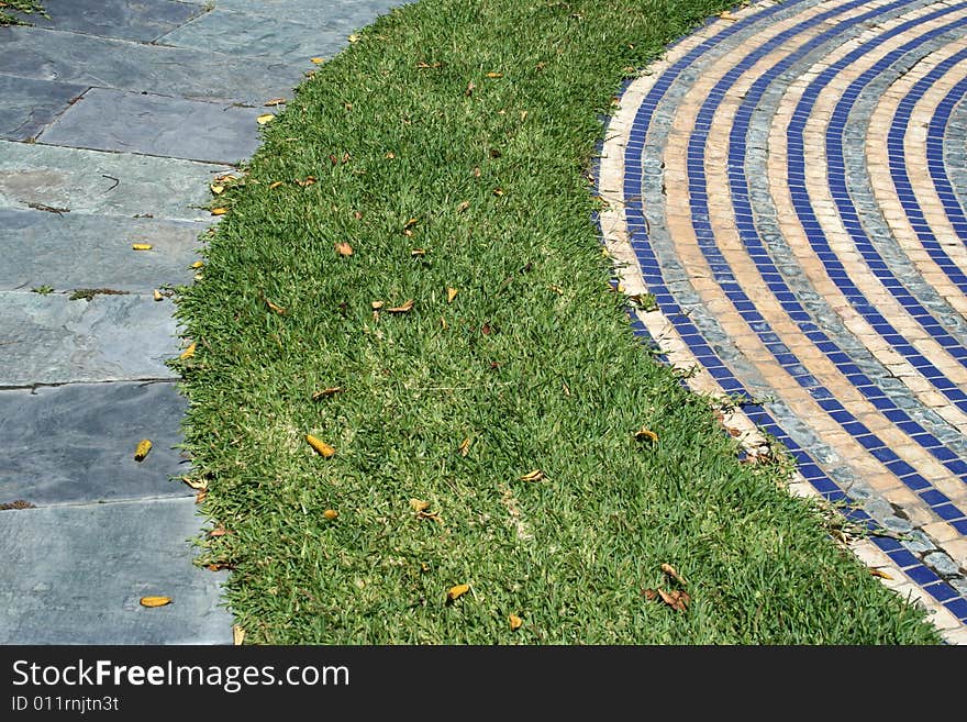 Way in grass between blue tiles and granite way