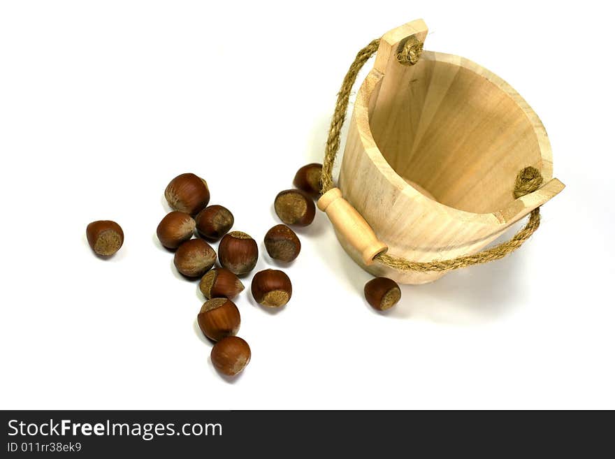 Hazelnuts and empty wooden busket on white background