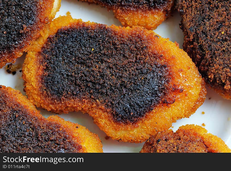 Slightly burnt chicken cutlets on the plate. Narrow depth of field. Slightly burnt chicken cutlets on the plate. Narrow depth of field.