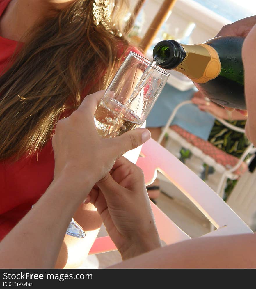 A girl holds her glass while the champagne is poured in. A girl holds her glass while the champagne is poured in