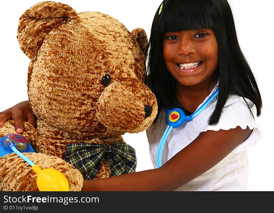 Beautiful 10 year old Indian girl playing doctor to a giant teddy bear. Beautiful 10 year old Indian girl playing doctor to a giant teddy bear.