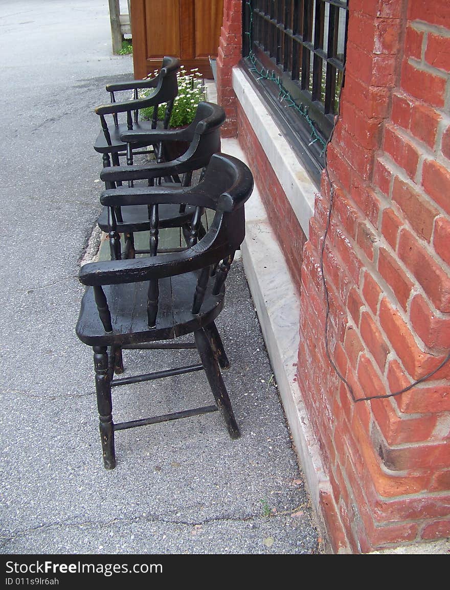 A row of chairs sit in front of a brick wall just
waiting for anyone who would like to sit a spell.