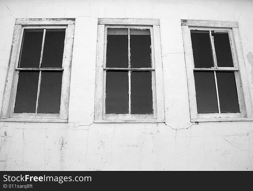 Black and white detail of three windows on the side of an abandoned building. Black and white detail of three windows on the side of an abandoned building