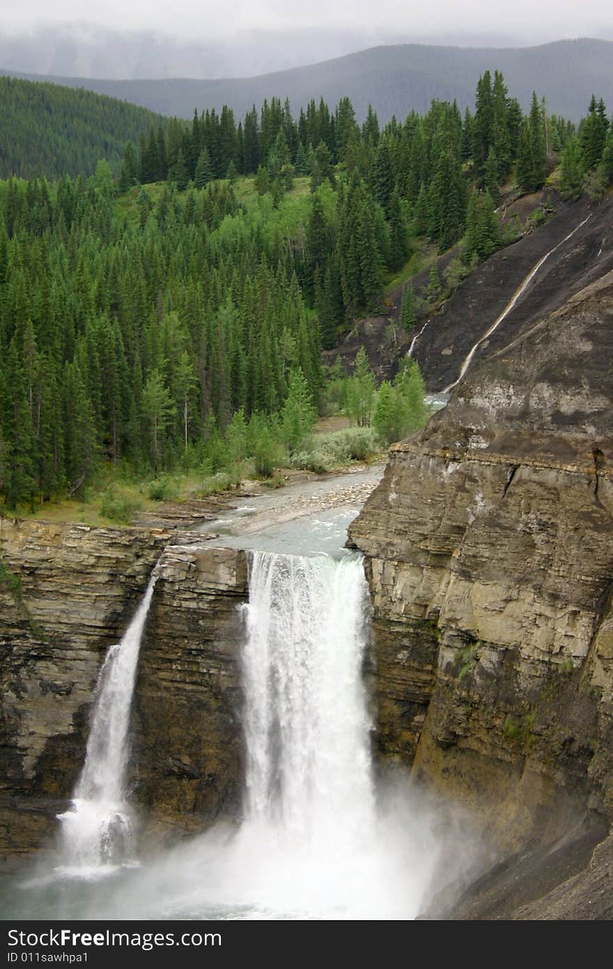 A powerful twin waterfall plunging over a cliff in the Canadian Rockies