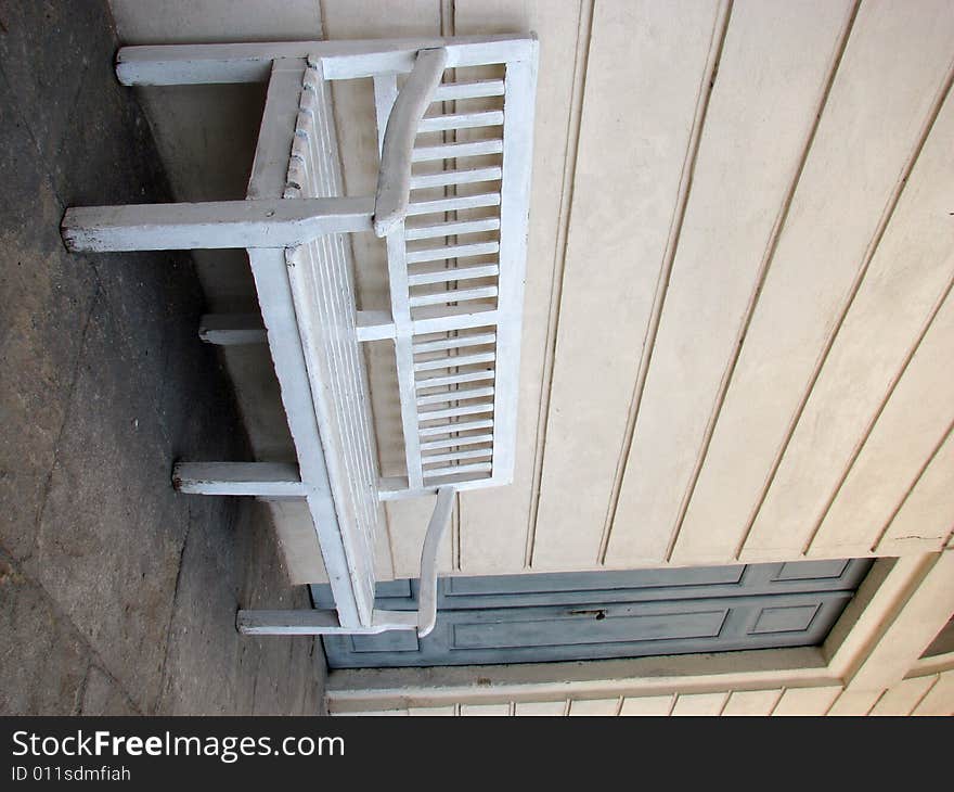 Empty white bench near blue door. Empty white bench near blue door