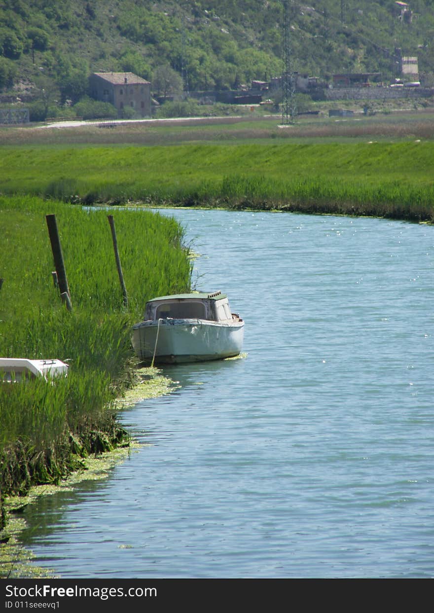 Rasa (Istria - Croatia) postcard: river runs through fertile green fields, boat on the river and a boat wreck in the grass 

*RAW format available